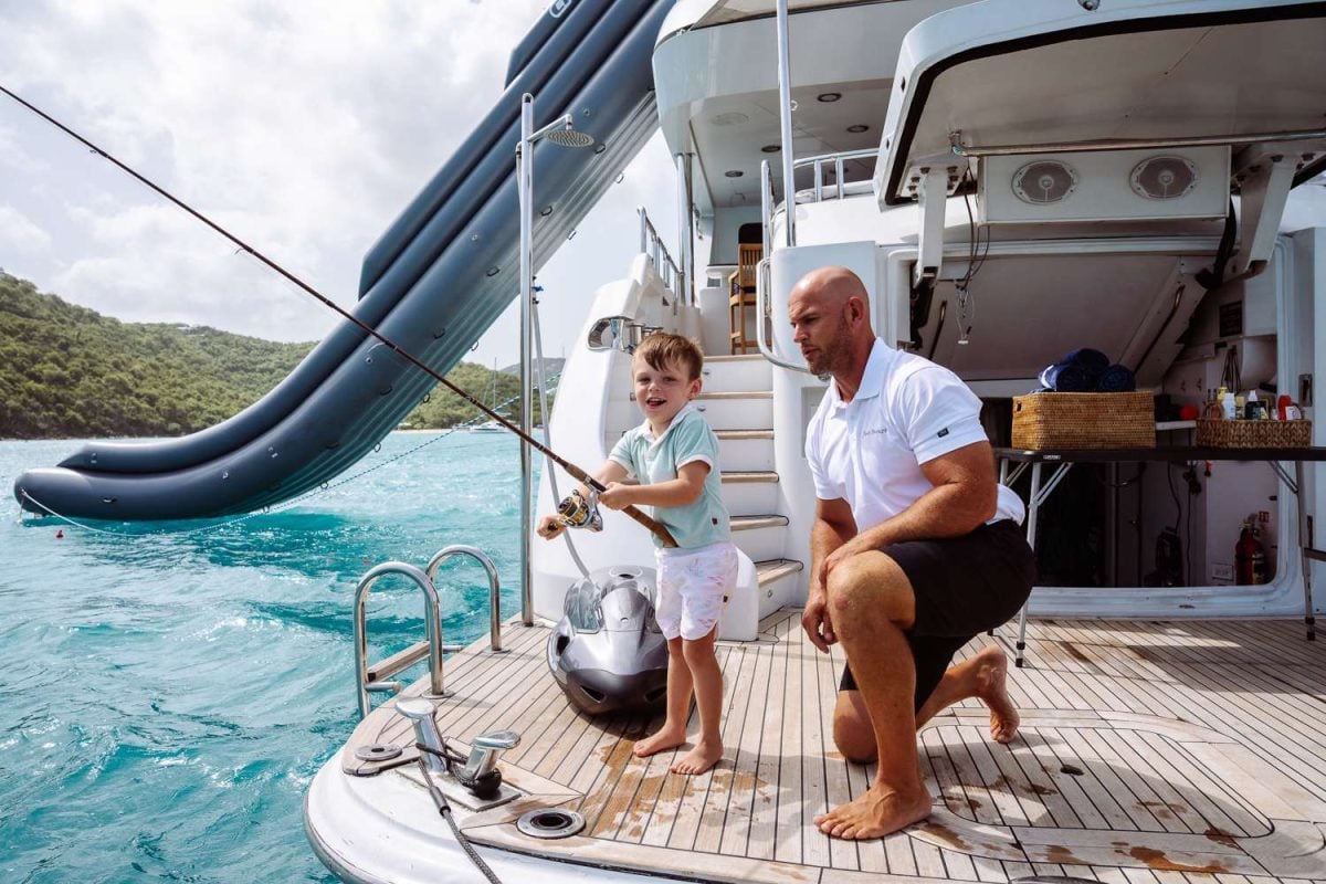 Father and young son fishing together off the stern of a luxury charter yacht in the British Virgin Islands