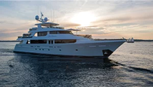 Far Niente motor yacht cruising at sunset with sailboats nearby