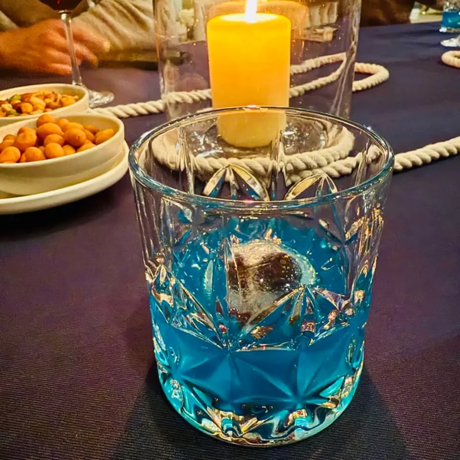 Blue cocktail with rope and candlelit table setting