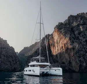 Almosta Road catamaran anchored between tall cliffs in dramatic landscape