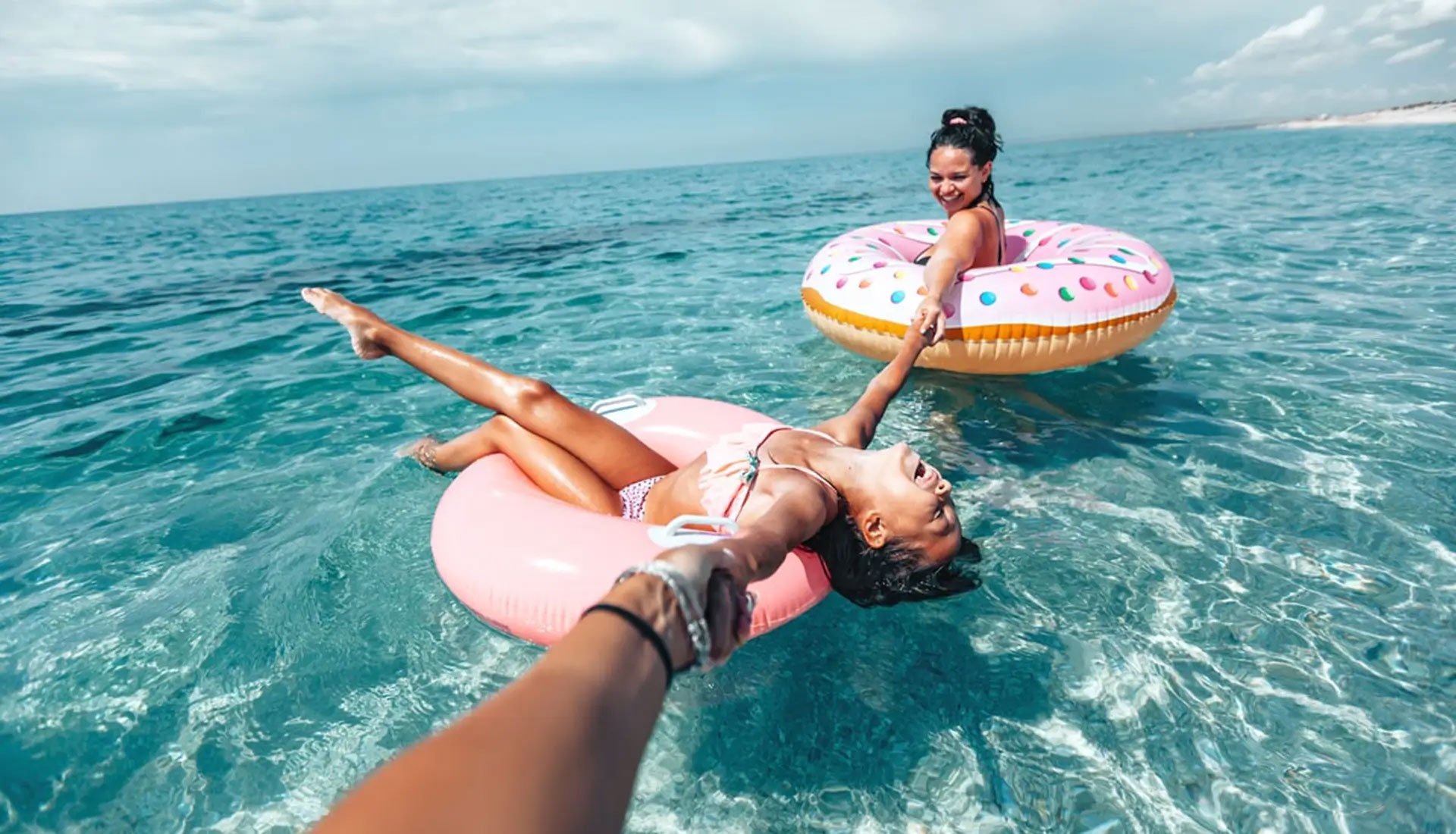 Guests relaxing on inflatables in clear Caribbean water during a yacht charter.