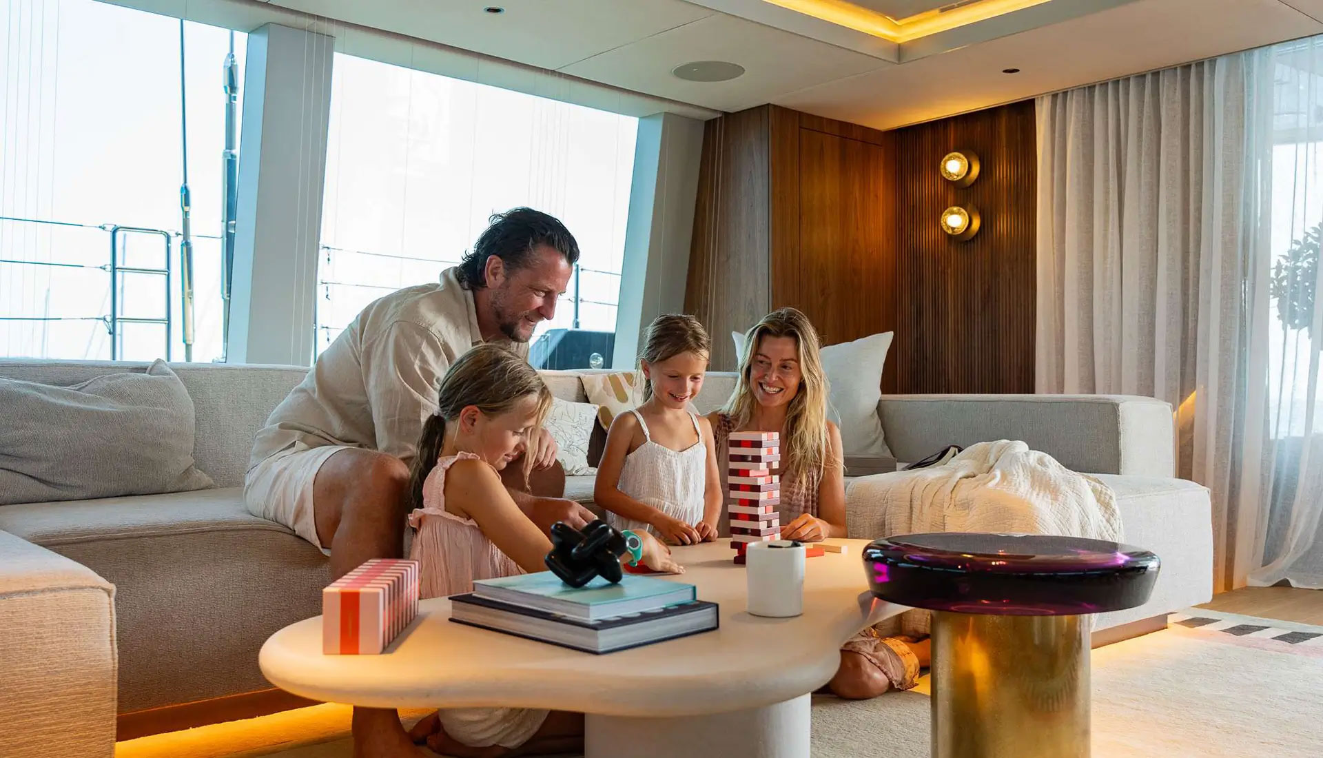 Family playing Jenga together inside a luxury sailing catamaran