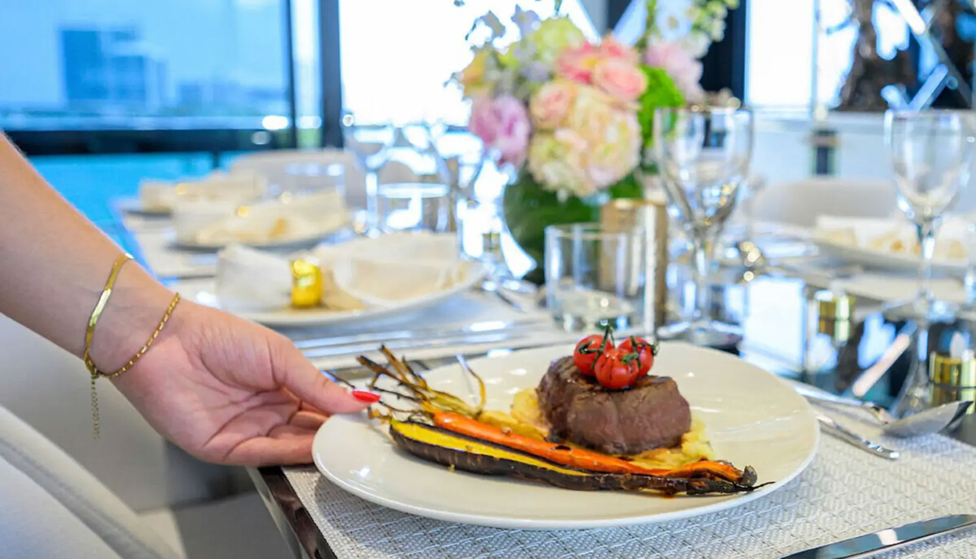 Elegant plated dinner served onboard a luxury yacht with vegetables and wine