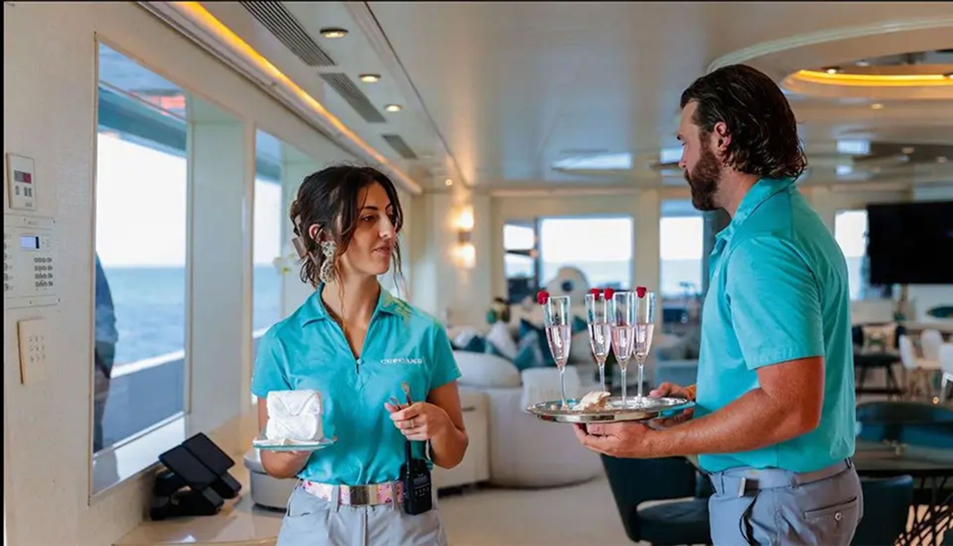 Professional yacht crew serving champagne on an all-inclusive charter
