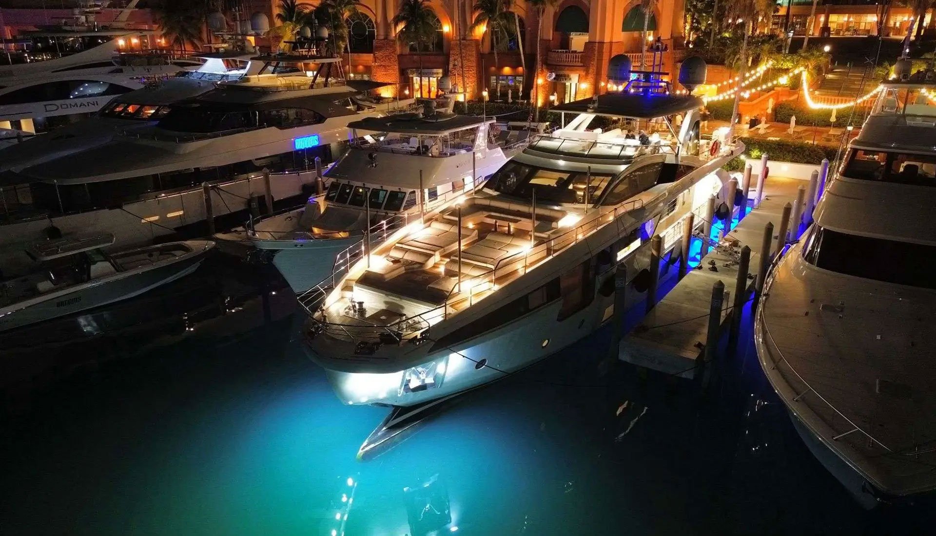Illuminated luxury motor yacht docked at night in a glowing harbor