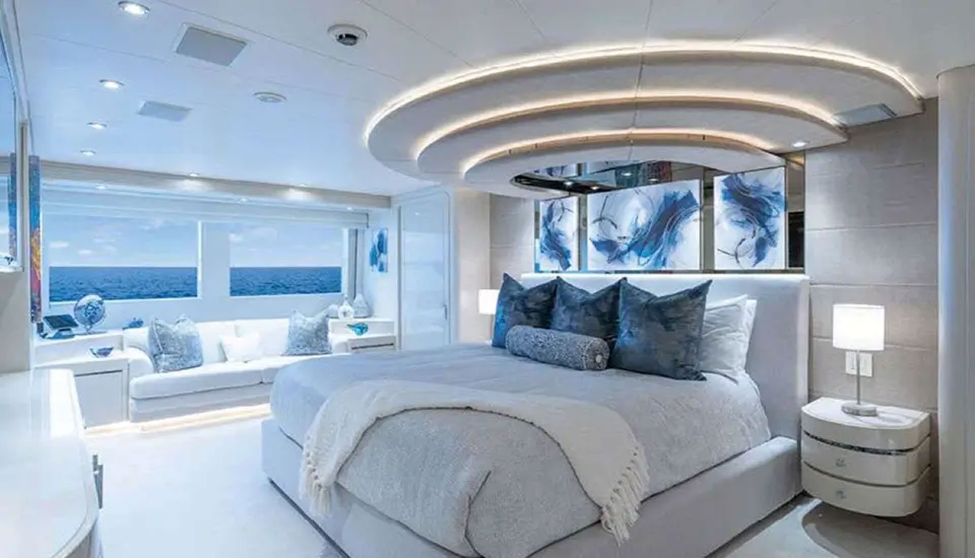 Luxury yacht primary suite with king-sized bed and ocean views, symbolizing the comfort of a sleep aboard the night before charter departure.