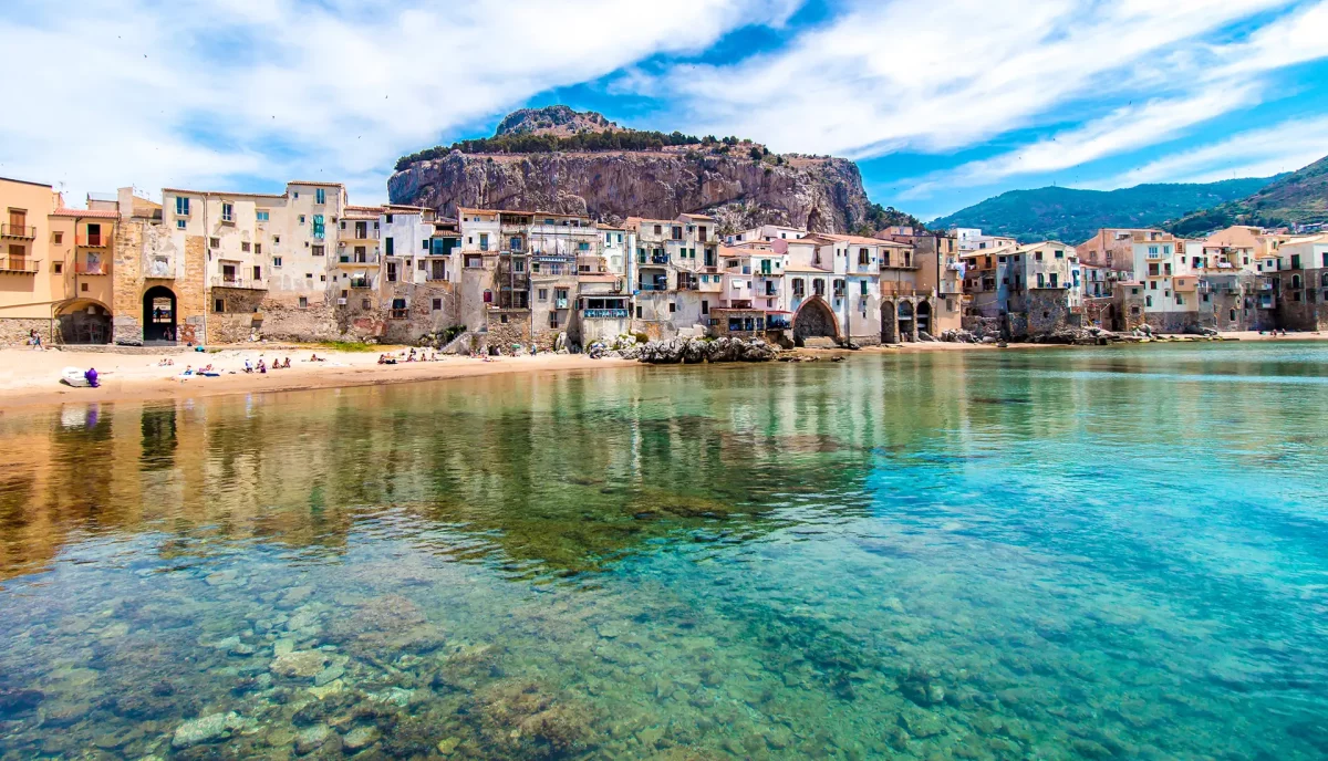 Cefalu beach town with Norman cathedral and La Rocca cliff Sicily coastline