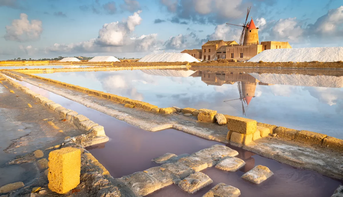 Marsala salt flats with traditional windmill and reflecting pools at sunset Sicily