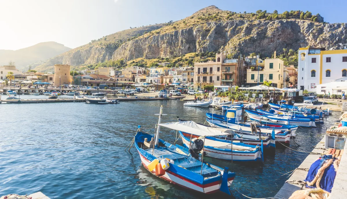 Palermo fishing harbor with traditional blue boats and cliff backdrop Sicily