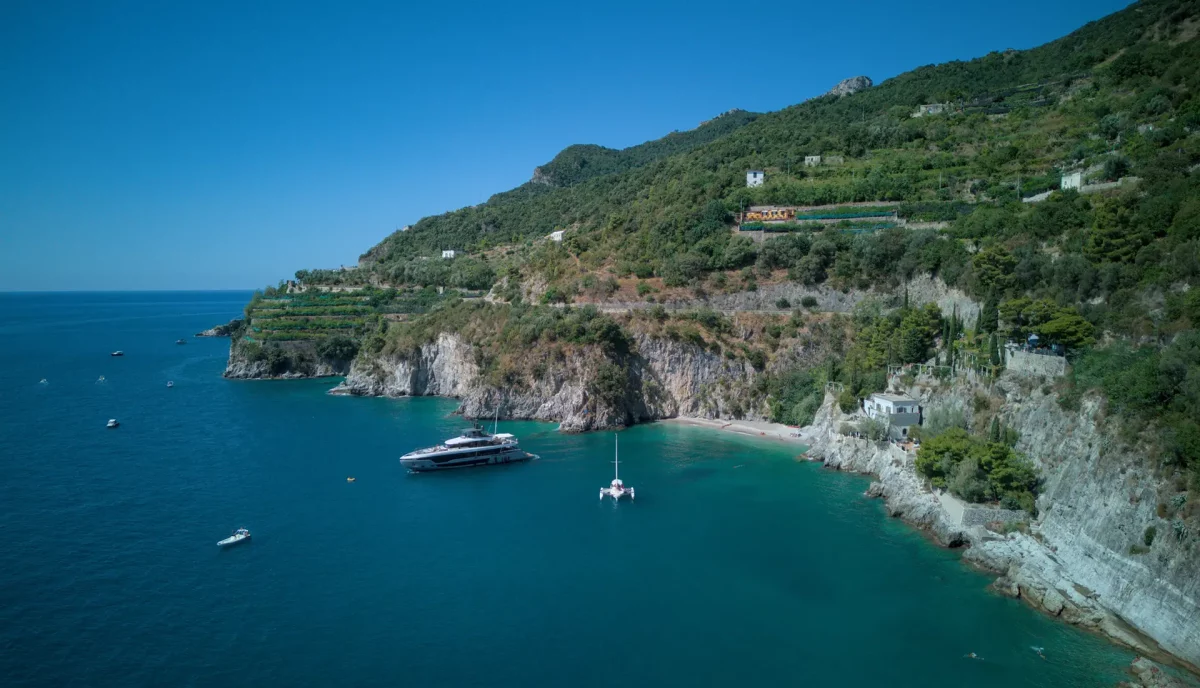 Luxury yacht anchored in secluded bay near Cetara on the Amalfi Coast with dramatic cliffs