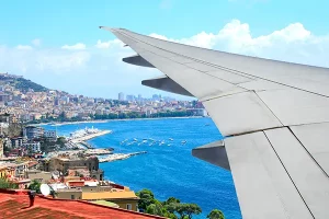 Airplane window view approaching Naples and Mediterranean coast of Italy with marina and blue waters