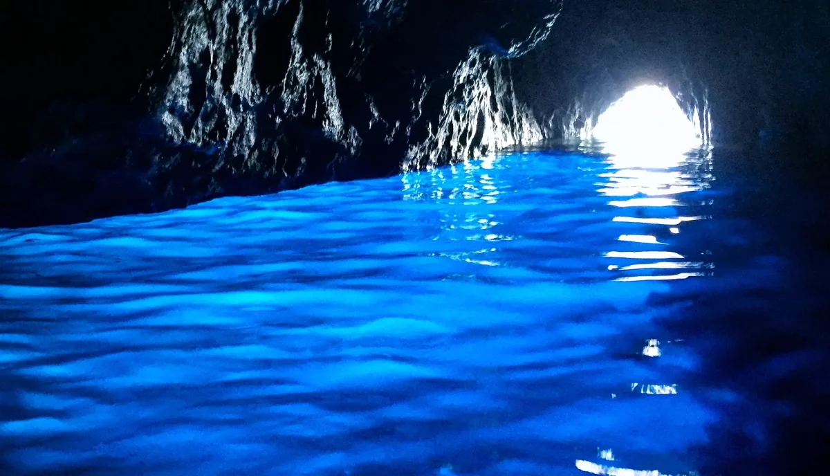 Inside the Blue Grotto cave in Capri showing magical blue illuminated water and cave entrance