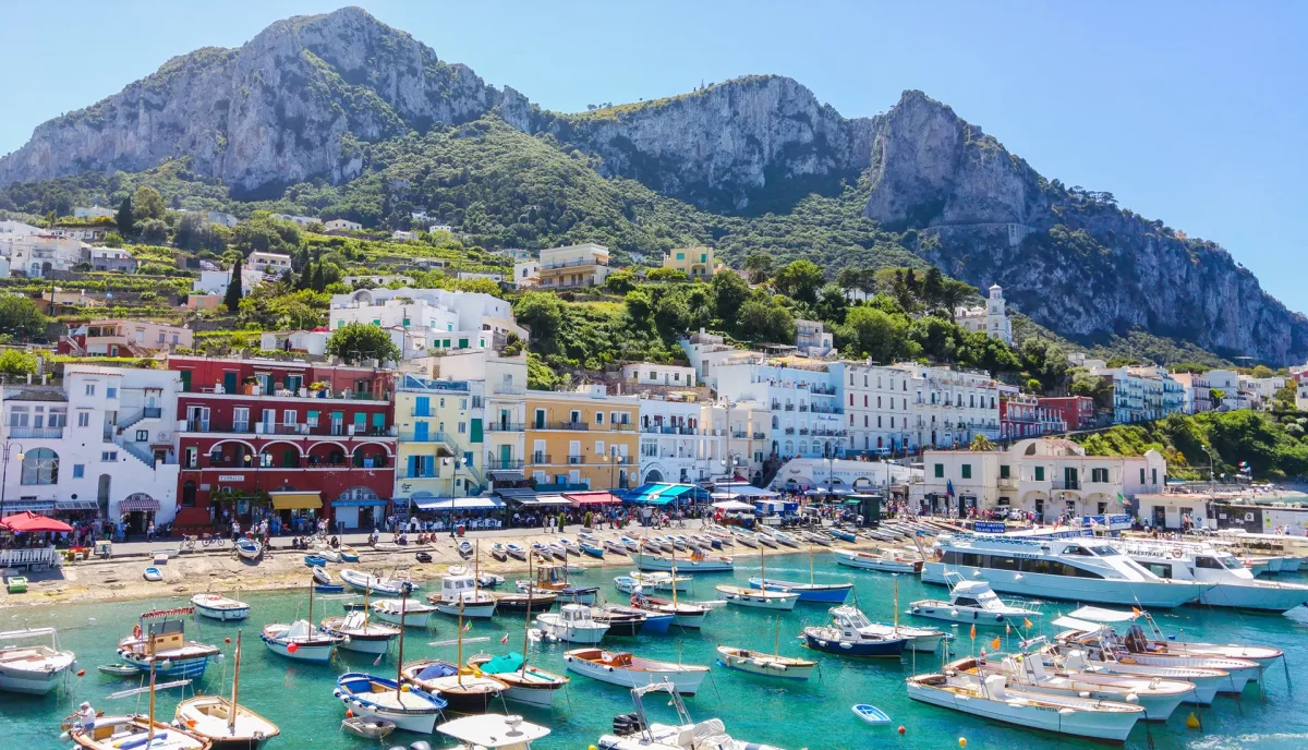 Capri Marina Grande harbor with colorful buildings, boats, and Monte Solaro mountain backdrop