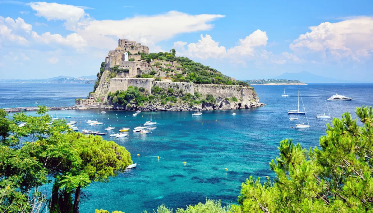 Aragonese Castle of Ischia with luxury yachts anchored in turquoise waters of the Bay of Naples