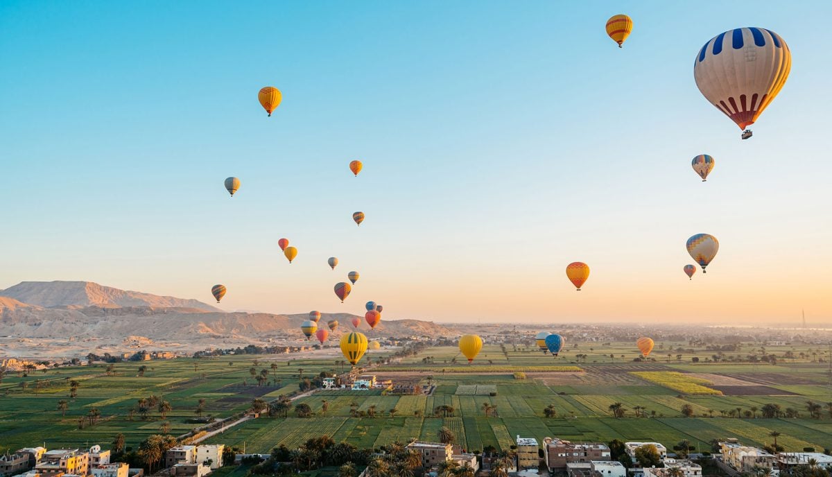 Hot air balloons floating over Valley of the Kings Luxor Egypt sunrise cultural excursion from Red Sea yacht charter