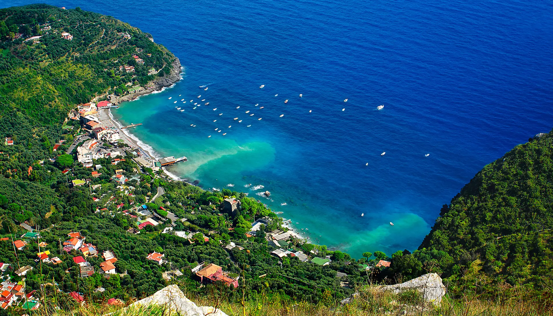 Marina del Cantone's turquoise bay with yachts anchored for swimming on the Sorrento Peninsula