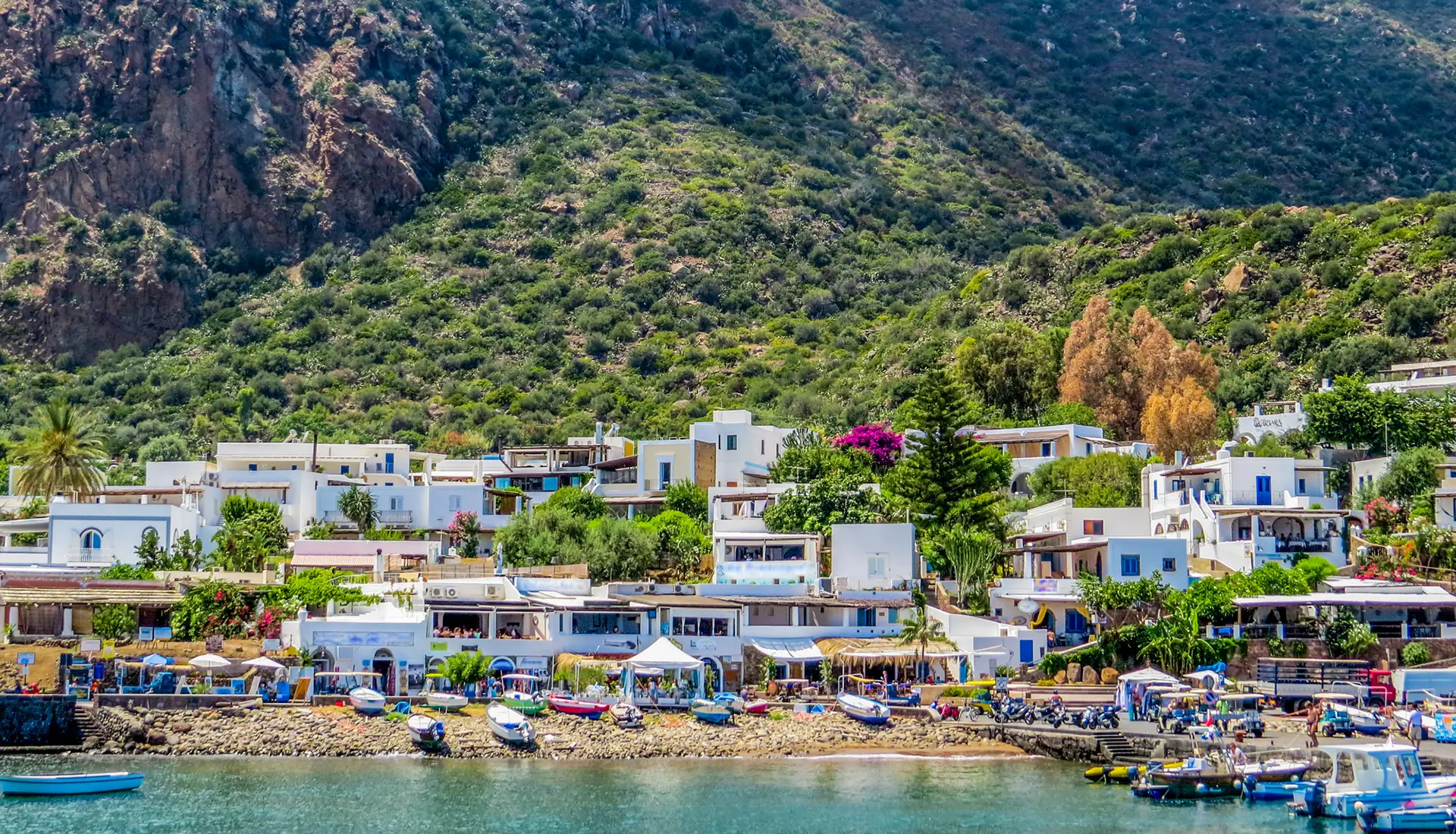Panarea village with white cubic houses nestled below green mountains on exclusive Aeolian island