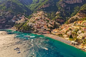 Aerial view of Positano beach with colorful houses cascading down cliffs and boats in turquoise waters