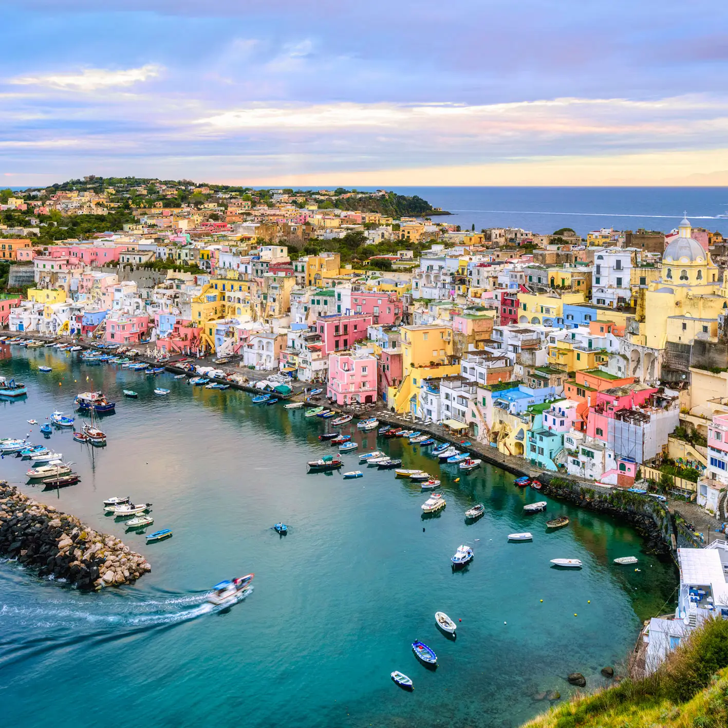 Procida Marina Corricella colorful harbor houses at sunrise with fishing boats anchored in calm waters