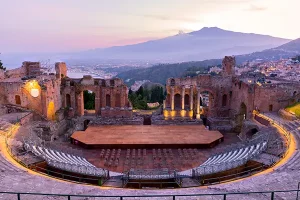 Ancient Greek amphitheater in Taormina Sicily at sunset with Mount Etna volcano in background
