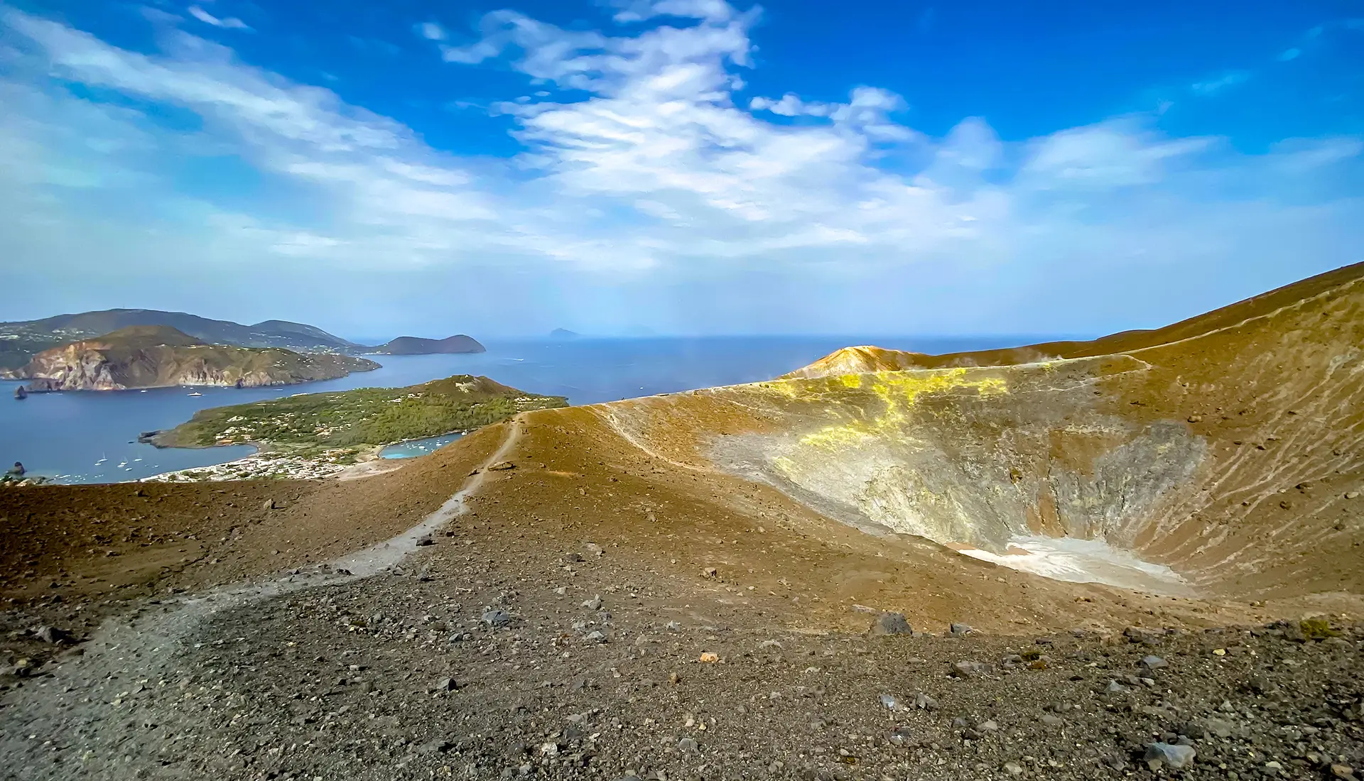 Vulcano Island volcanic crater with yellow sulfur deposits and hiking path on rim