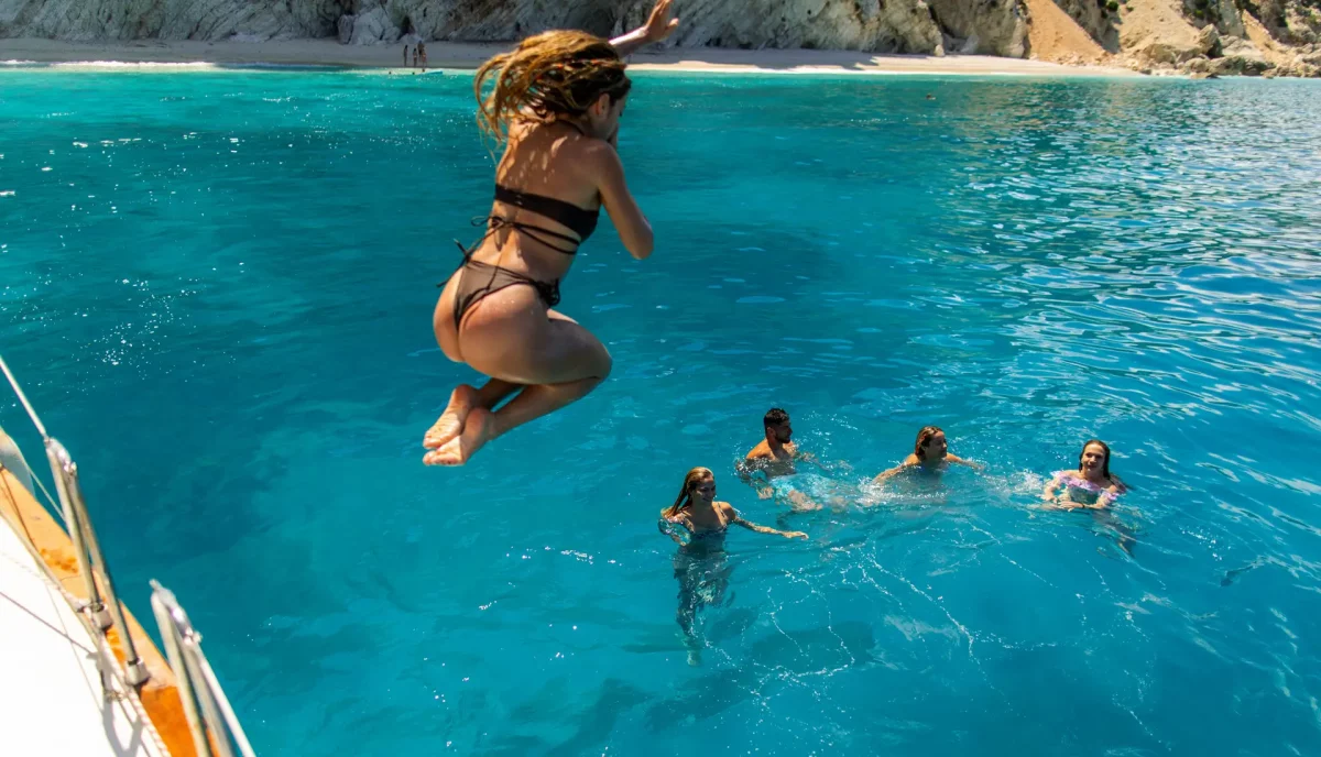 Wedding guests jumping and swimming in turquoise Caribbean waters from luxury charter yacht swim platform