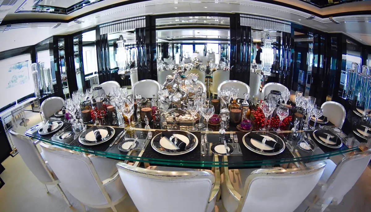 Elegant formal dining table aboard luxury yacht with crystal glassware and fine china settings
