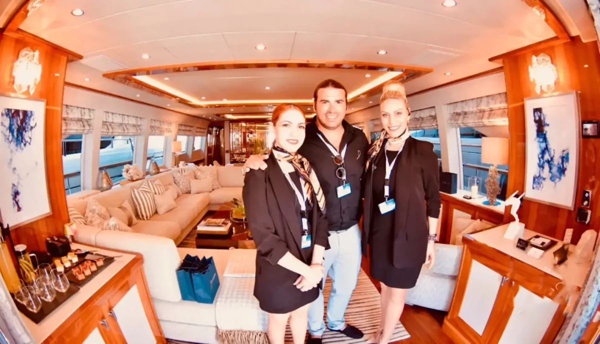 Professional yacht crew in uniform standing in luxury yacht salon interior
