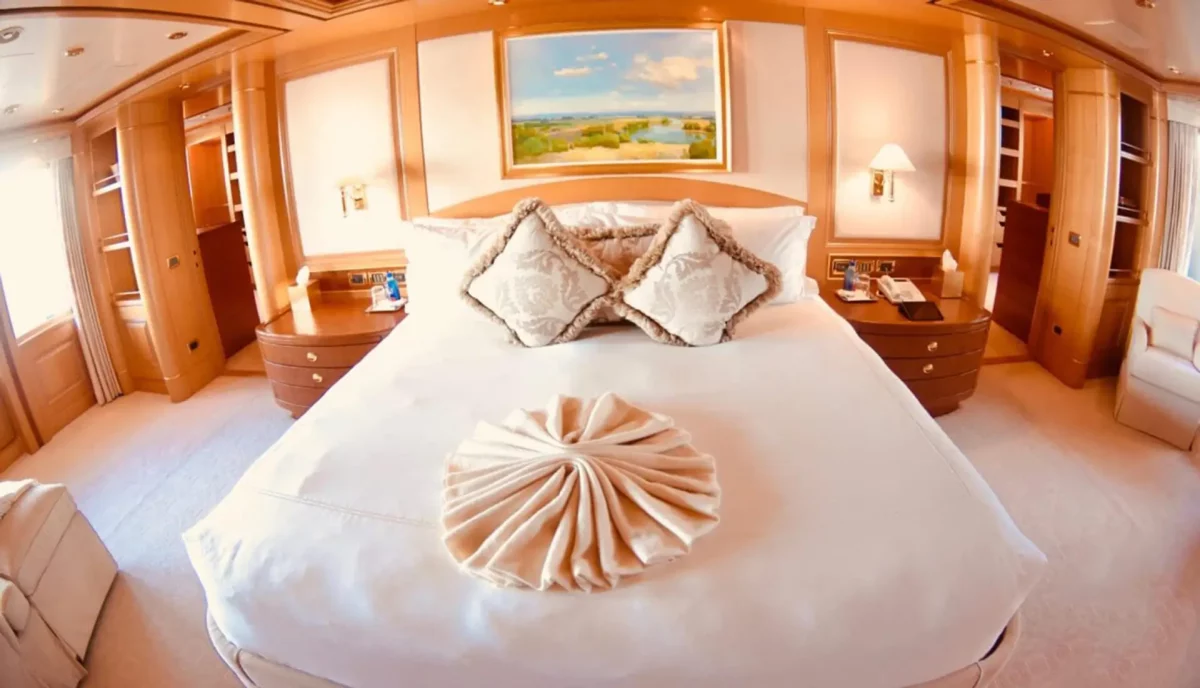 Luxury yacht primary stateroom with elegant bedding and polished wood finishes