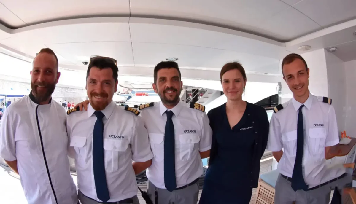 Professional yacht charter crew in white uniforms standing together on luxury yacht deck