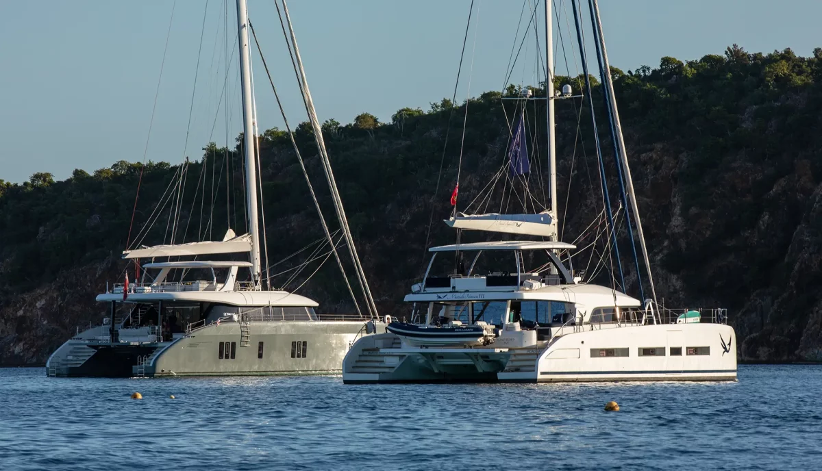 Two luxury catamarans anchored together at peaceful bay showing tandem yacht charter options