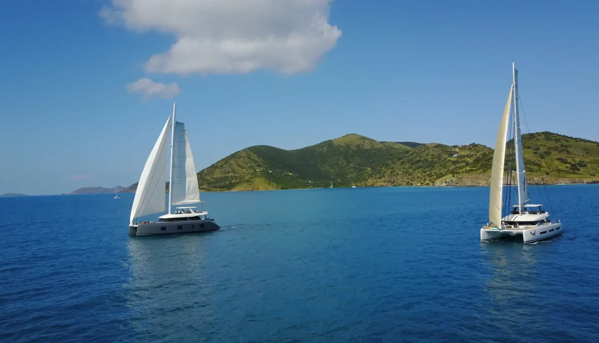 Two luxury sailing catamarans under sail showing different yacht charter types and options available