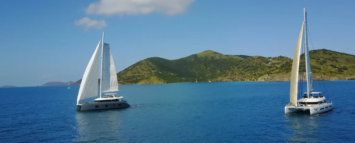 Two luxury sailing catamarans under sail showing different yacht charter types and options available