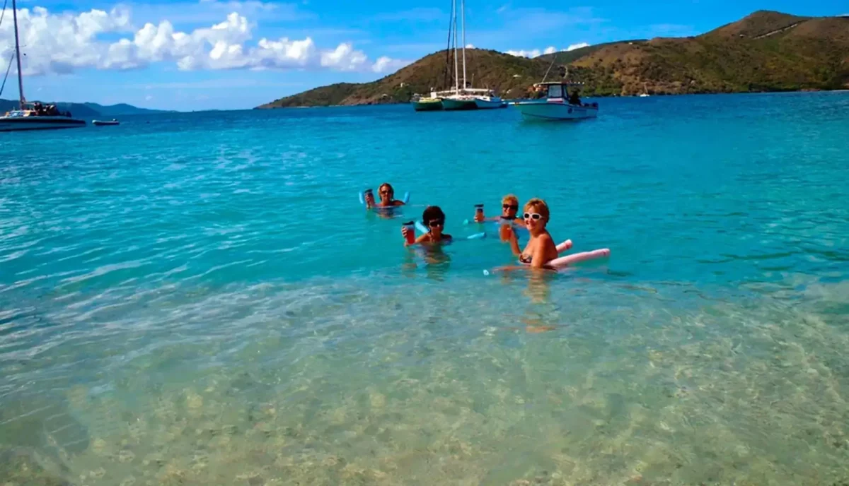 Yacht charter guests swimming and enjoying water activities near anchored catamaran