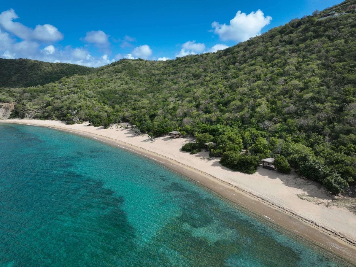 White Bay beach on Peter Island with turquoise water and lush green hillside in the British Virgin Islands