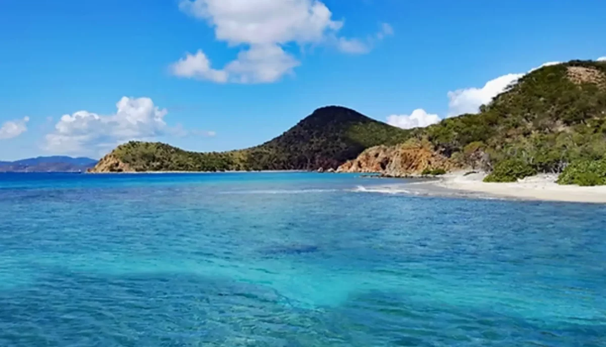 Key Bay on Peter Island showing secluded anchorage with rocky coastline and blue Caribbean water in the British Virgin Islands