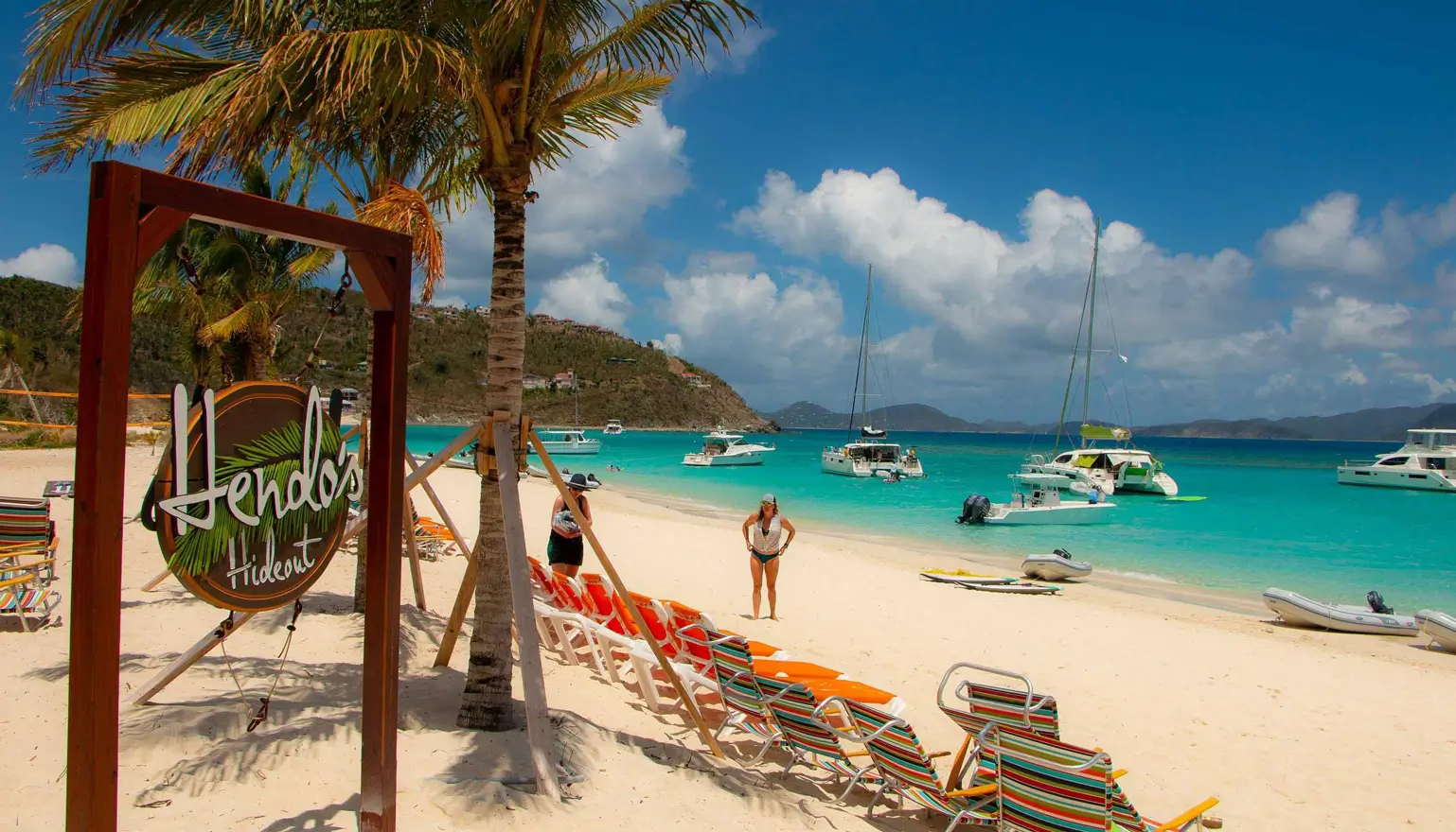Hendo's Hideout beach bar sign on White Bay, Jost Van Dyke, British Virgin Islands with charter yachts anchored in turquoise water