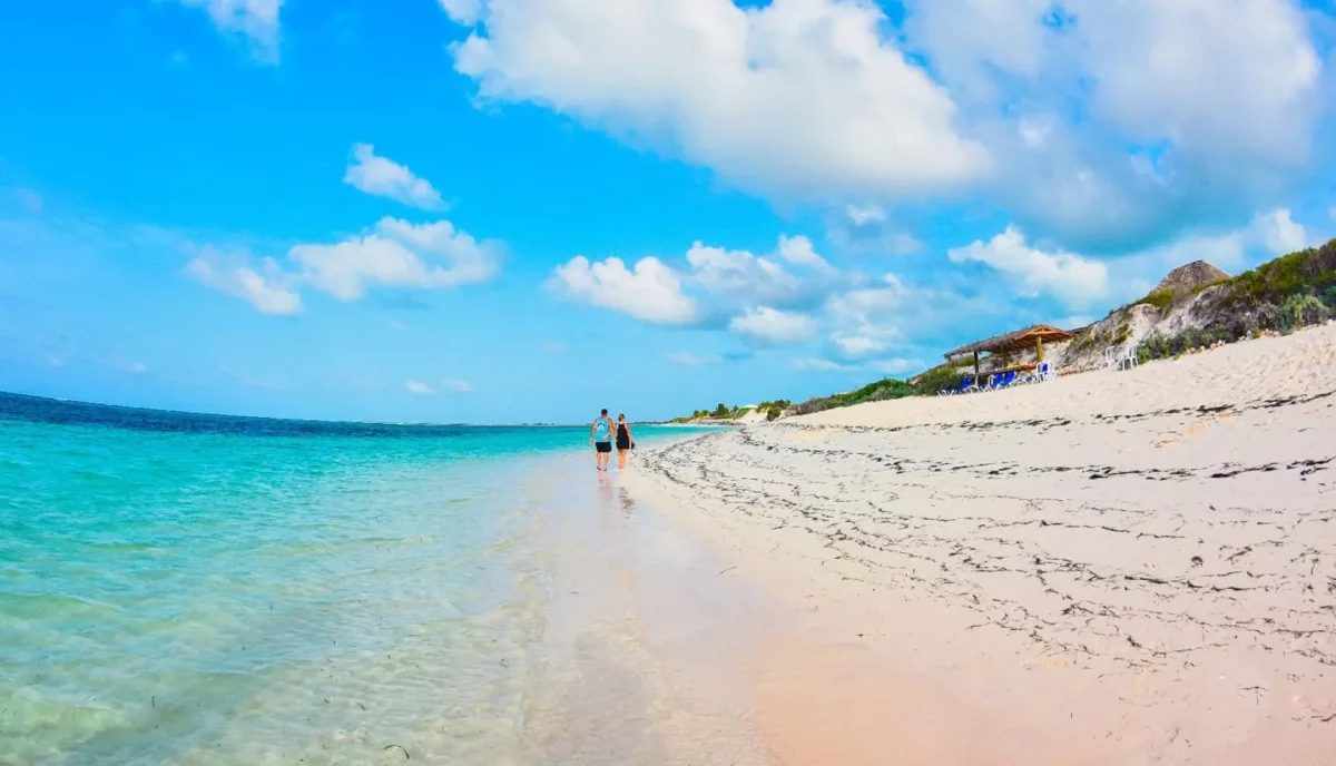 Couple walking on the long empty white sand beach at Anegada Beach Club on the north shore of Anegada BVI