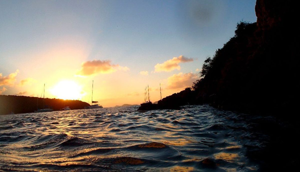 Golden sunset over the Bight anchorage at Norman Island BVI with yachts silhouetted against the sky