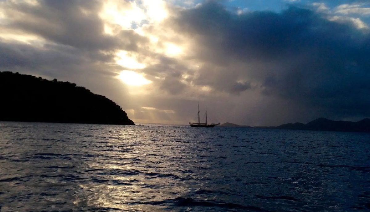 Tall ship silhouetted at twilight anchored off Norman Island BVI