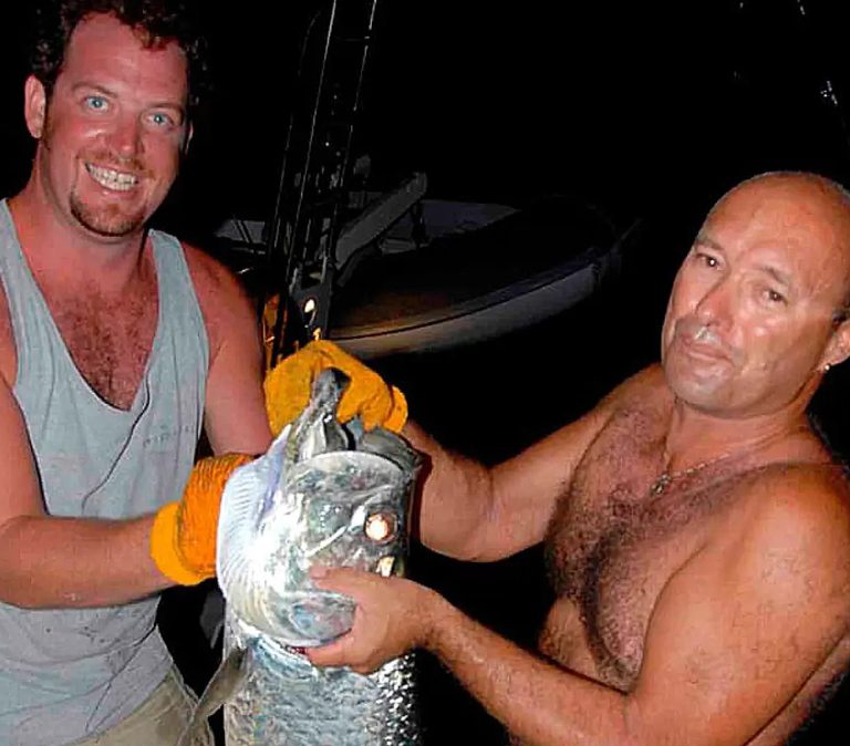 Two anglers holding a tarpon caught at night from a charter yacht in the British Virgin Islands